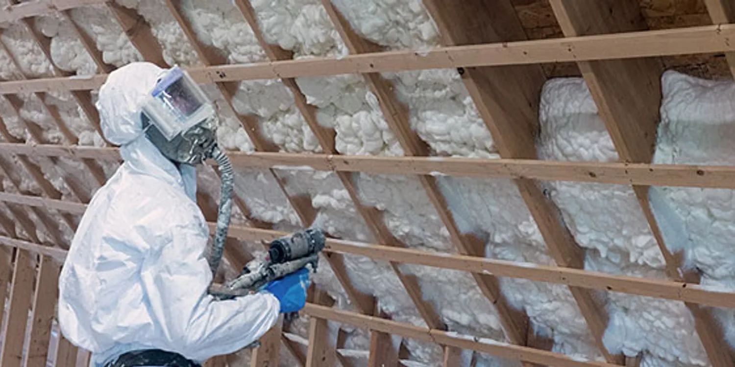 Installer working on spray foam inside framing