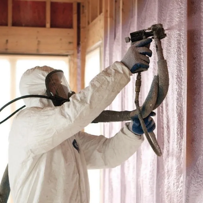 Installer spraying foam on wall framing